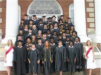 group of graduates posing on steps in regalia