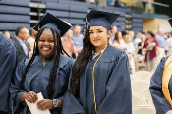 two smiling graduates in cap and gown