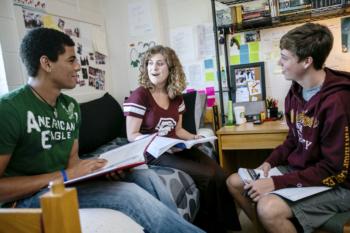 three students studying in dorm room