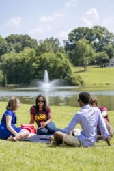 students relaxing by a lake with fountain